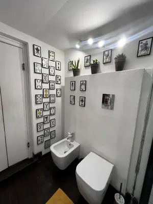 a bathroom with a toilet and pictures on the wall at Appartamento Beatrice in Palermo