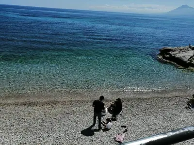 a man and a woman standing on a rocky beach at Sea sicily home in Santa Flavia
