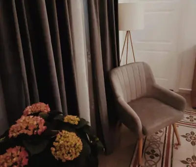 a living room with a chair and flowers in front of a window at Piazza Vittoria Apartment in Carini