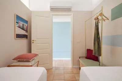 a bedroom with two beds and a door at Sole di Giada by DomuSicily in Mondello