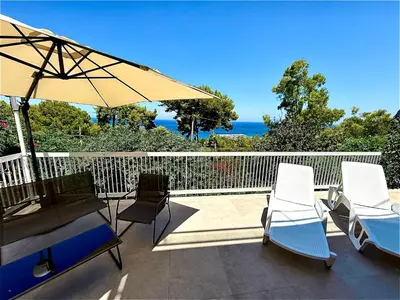 a patio with chairs and an umbrella and the ocean at Porta Addaura in Palermo