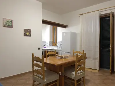 a kitchen with a wooden dining table and chairs at La Capinera Holidays in Santa Flavia