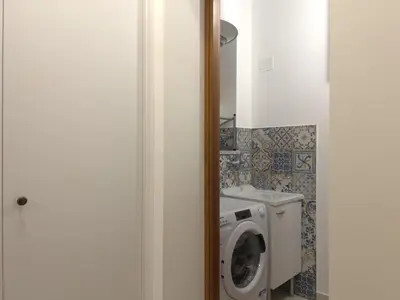 a bathroom with a washing machine and a washer at La Capinera Holidays in Santa Flavia
