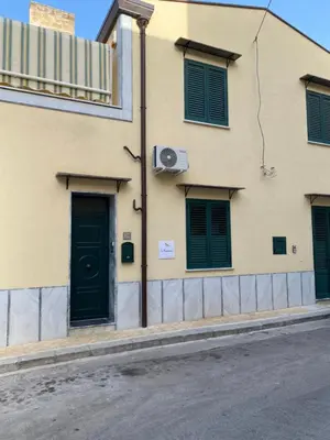 a building with green doors on a street at La Capinera Holidays in Santa Flavia
