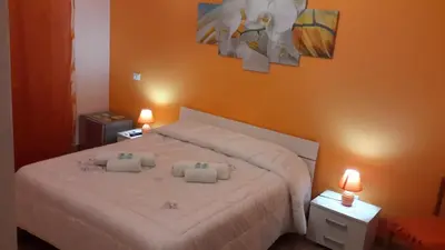 a bedroom with a bed with orange walls and two lights at Case Saniela in Terrasini