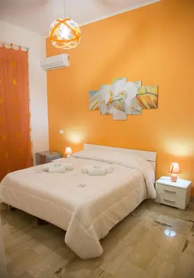 a bedroom with a large bed with an orange wall at Case Saniela in Terrasini