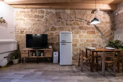 a kitchen with a refrigerator and a table with a tv at Loft Vetriera in Palermo