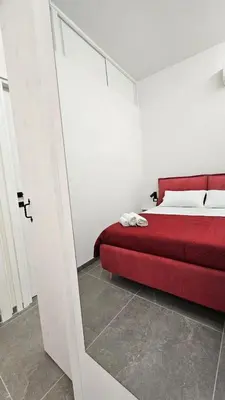 a red bed in a white room with a red couch at Suites Masculu & Fimmina in Palermo