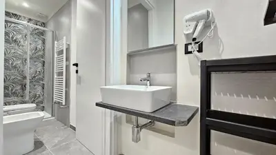 a white bathroom with a sink and a toilet at Suites Masculu & Fimmina in Palermo
