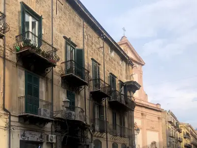 a building with green shutters and balconies on a street at Calderai 82 suites 1 e 2 in Palermo