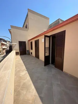 a building with wooden doors and a large patio at Gravina in Trappeto