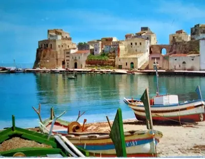 a group of boats sitting on the beach in front of a city at little Italy in Castellammare del Golfo