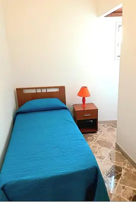 a bedroom with a blue bed and a table with a lamp at little Italy in Castellammare del Golfo