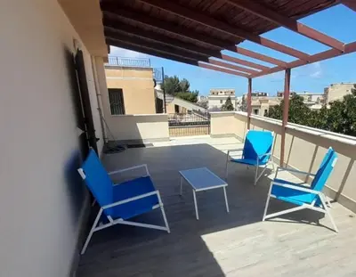 three blue chairs and a table on a balcony at little Italy in Castellammare del Golfo