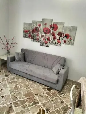 a couch in a living room with three paintings on the wall at little Italy in Castellammare del Golfo