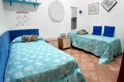 a bedroom with two beds with blue sheets and a mirror at Casa Tequi a 200mt dal mare in Terrasini