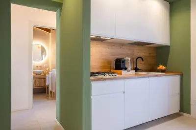 a kitchen with white cabinets and a green wall at Le Terrazze dei Candelai 