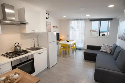 a kitchen and living room with a couch and a table at Appartamento con terrazza in Isola delle Femmine