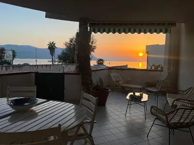 a patio with a table and chairs and the sunset at Isola delle Femmine Holiday Nancy in Isola delle Femmine