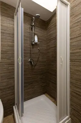 a shower in a bathroom with a wooden wall at Isola delle Femmine Holiday Nancy in Isola delle Femmine