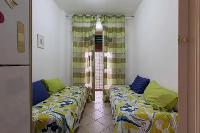a room with two beds and a window at Isola delle Femmine Holiday Nancy in Isola delle Femmine
