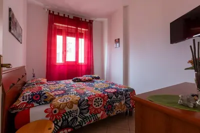 a bedroom with a bed with a colorful comforter and a window at Isola delle Femmine Holiday Nancy in Isola delle Femmine
