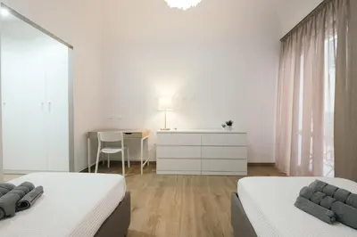 a white bedroom with two beds and a desk at La Casa di Ale in Palermo