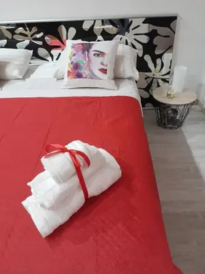 a bed with a red blanket with towels on it at Sea Holiday Orchidea in Palermo