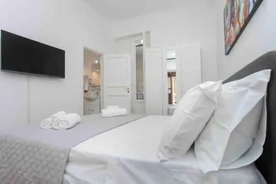 a white bedroom with a large bed with a flat screen tv at The house Politeama Palermo Historic center in Palermo