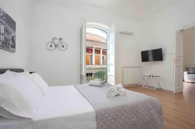 a bedroom with a white bed and a large window at The house Politeama Palermo Historic center in Palermo