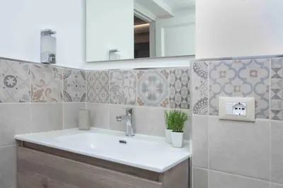 a bathroom with a sink and a mirror and tiles at The house Politeama Palermo Historic center in Palermo