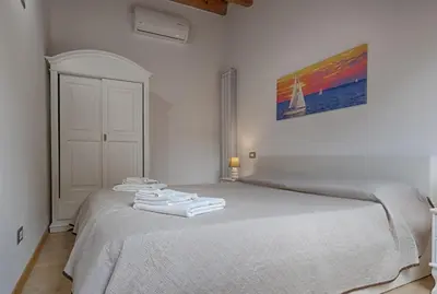 a white bedroom with a bed with towels on it at GuestHost - Il Piccolo Scrigno - Functional & Central Studio in Castellammare del Golfo