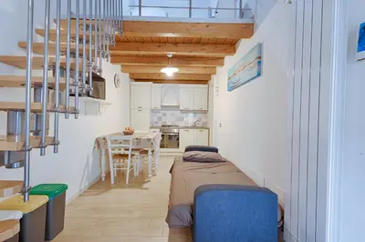 a room with a bed and a table and a kitchen at GuestHost - Il Piccolo Scrigno - Functional & Central Studio in Castellammare del Golfo