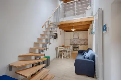 a spiral staircase in a living room with a blue couch at GuestHost - Il Piccolo Scrigno - Functional & Central Studio in Castellammare del Golfo