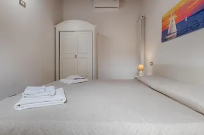 a white bedroom with a bed with towels on it at GuestHost - Il Piccolo Scrigno - Functional & Central Studio in Castellammare del Golfo