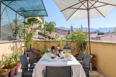 a table and chairs on a balcony with an umbrella at Palazzo Sant'Agostino in Palermo