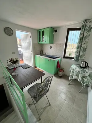 a kitchen with green cabinets and a table and chairs at Mille Lire Peppe's Home in Palermo
