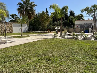 a yard with chairs and a building with palm trees at Scopello Guidaloca Villas in Scopello