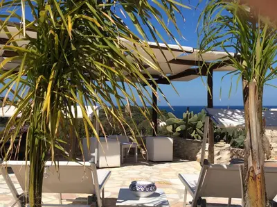 a patio with chairs and a view of the ocean at Scopello Guidaloca Villas in Scopello