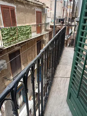 a balcony with a fence and a dog on a building at Quiet and comfortable apartment in Palermo city centre in Palermo