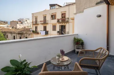 a patio with chairs and a table on a balcony at Conte Ruggero Apartment by DomuSicily in Palermo