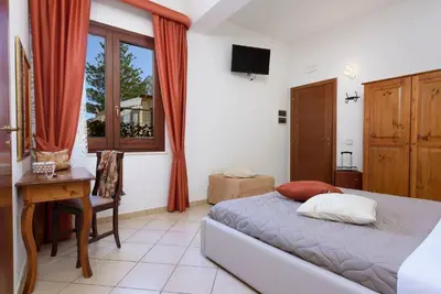 a bedroom with a bed and a desk and a window at Hotel La Darsena in San Vito lo Capo