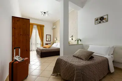 a hotel room with two beds and a suitcase at Hotel La Darsena in San Vito lo Capo