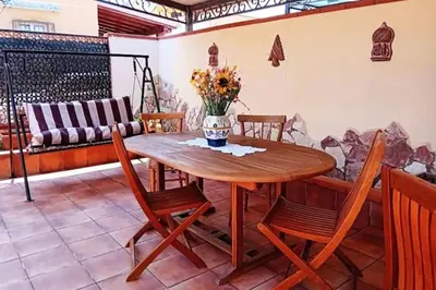 a wooden table with chairs and a vase of flowers at Villa Rosetta vacanze al mare in Carini