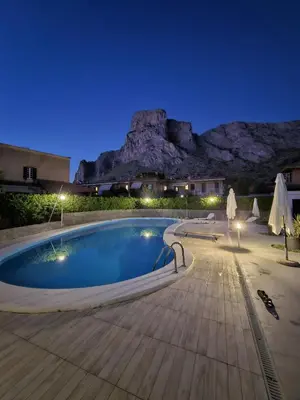 a swimming pool at night with a mountain in the background at Villa Eufrosine in Palermo