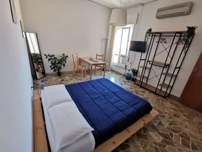 a bedroom with a bed with blue sheets and a desk at La Casa del Capo in Palermo