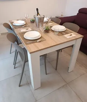 a wooden table with plates and wine glasses on it at Clio's House - Mondello in Mondello