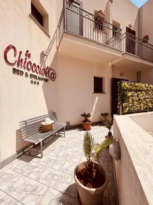 a patio with a bench and potted plants in front of a building at La Chiocciola 2 Bed&Breakfast in Castelluzzo