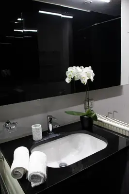 a bathroom sink with towels and a vase of flowers at Luxury suite 2 min dal Politeama - Free Parking in Palermo