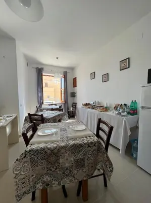 a dining room with two tables and a refrigerator at B&B Marco Polo in Terrasini